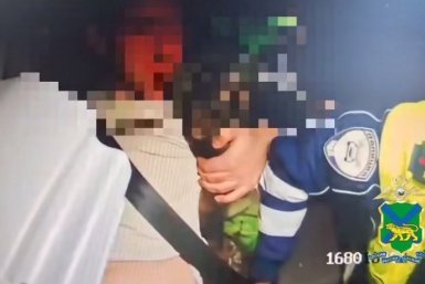 Задержанный мотоциклист в патрульном автомобиле стоп-кадр из видео, размещенном пресс-службой полиции Приморья