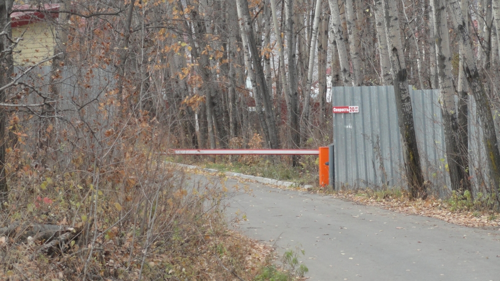Въезд в поселок преграждает шлагбаум.